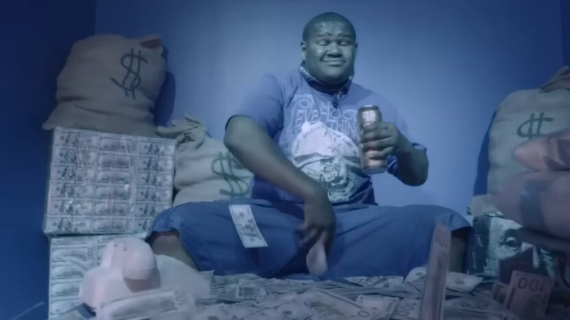 Crip Mac surrounded by large stacks of money and bags marked with dollar signs